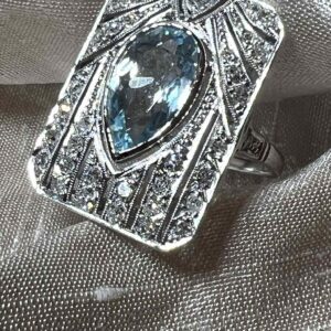 Elegant silver ring with a pear-shaped blue gemstone and diamond accents.