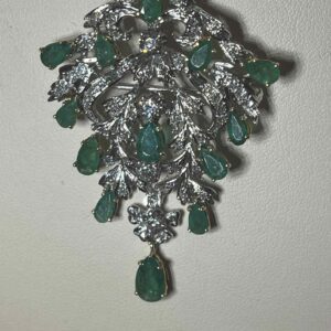 Intricate silver and emerald pendant with detailed leaf motifs.