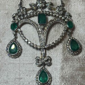 Vintage silver brooch with green gemstones in an ornate design.
