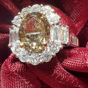 Elegant ring with a large central gemstone surrounded by diamonds on a red fabric.